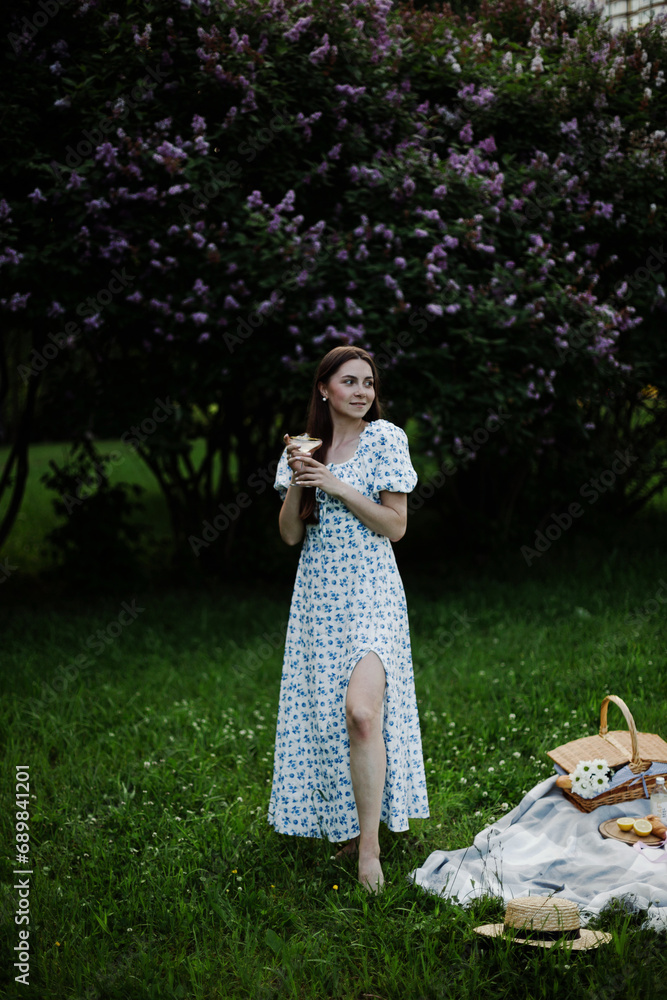 Naklejka premium Young woman in floral dress on a picnic in the park