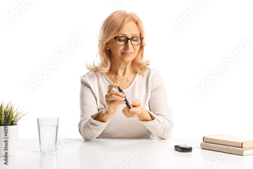 Woman injecting insulin pen in finger and sitting at a table