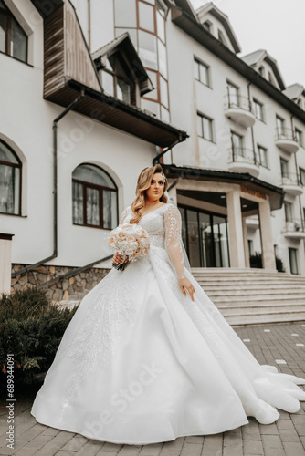 Beautiful bride with a wedding bouquet of flowers, attractive woman in a wedding dress with a long veil. Happy bride woman. Bride with wedding makeup and hairdo. Winter wedding © Марина Дочинець