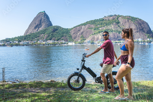Jovem casal caminhando pela costa, conversando, empurrando uma bicicleta. photo