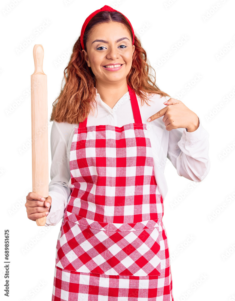 Young latin woman wearing apron holding kneader pointing finger to one self smiling happy and proud Young latin woman wearing apron holding kneader pointing finger to one self smiling happy and proud