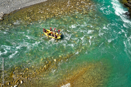 White water rafting.  Adventure and sport. A yellow raft floating among the rocks on the crystal clear, blue-green water. Perpendicular drone view of the rafters floating on Vjose river, Albania. photo