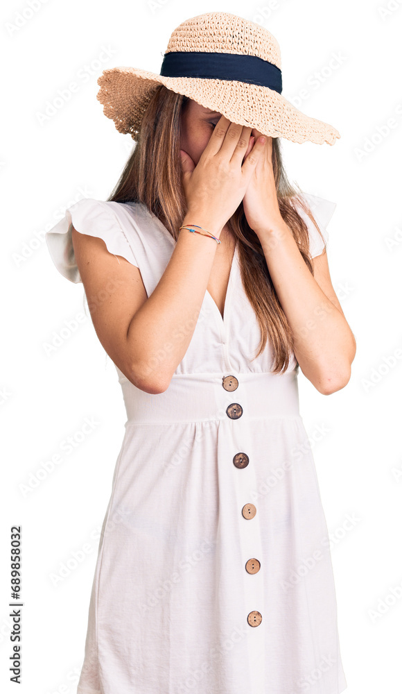 Young beautiful blonde woman wearing summer dress and hat with sad expression covering face with hands while crying. depression concept. Young beautiful blonde woman wearing summer dress and hat with sad expression covering face with hands while crying. depression concept.