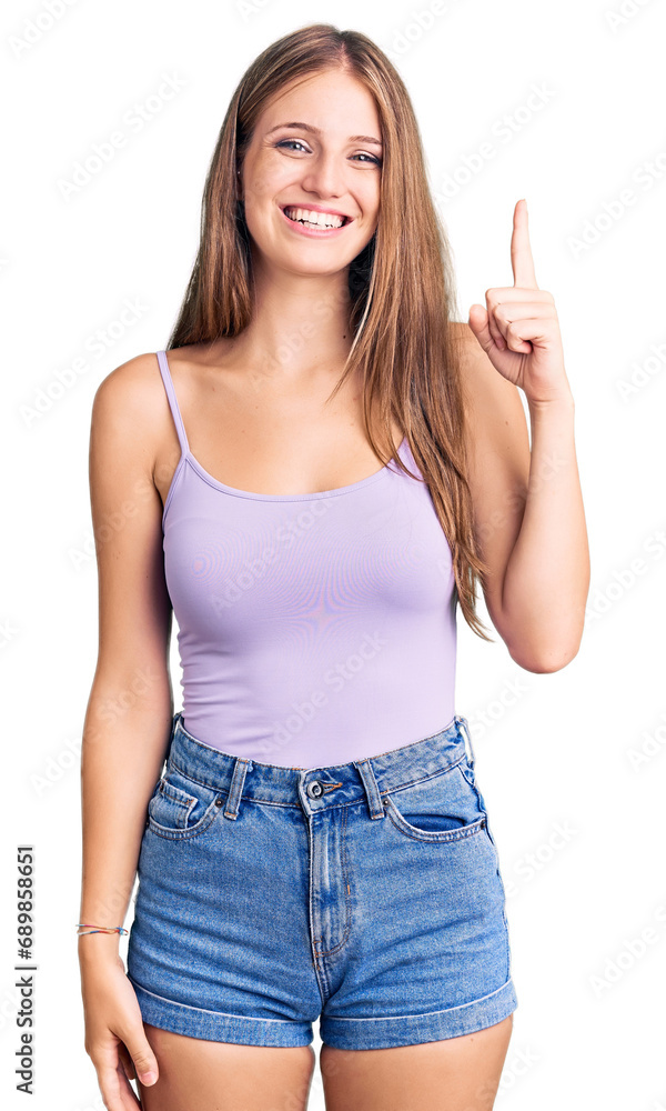 Young beautiful blonde woman wearing casual style with sleeveless shirt pointing finger up with successful idea. exited and happy. number one. Young beautiful blonde woman wearing casual style with sleeveless shirt pointing finger up with successful idea. exited and happy. number one.