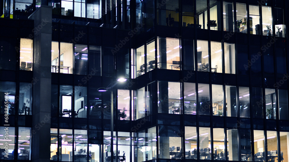 Fragment of the glass facade of a modern corporate building at night. Modern glass office in city. Fragment of the glass facade of a modern corporate building at night. Modern glass office in city.