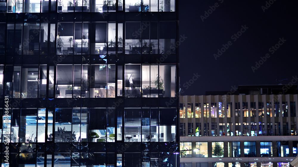 Fragment of the glass facade of a modern corporate building at night. Modern glass office in city. Big glowing windows in modern office buildings at night, in rows of windows light shines. Fragment of the glass facade of a modern corporate building at night. Modern glass office in city. Big glowing windows in modern office buildings at night, in rows of windows light shines.
