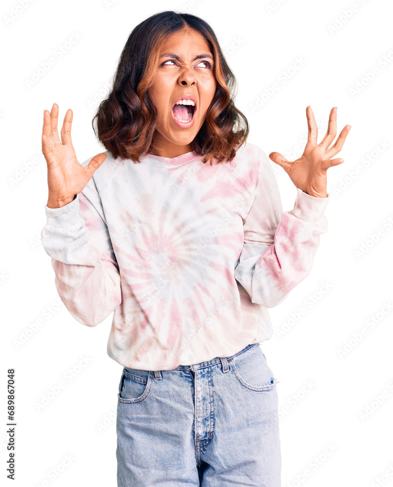 Young beautiful mixed race woman wearing casual tie dye sweatshirt crazy and mad shouting and yelling with aggressive expression and arms raised. frustration concept. Young beautiful mixed race woman wearing casual tie dye sweatshirt crazy and mad shouting and yelling with aggressive expression and arms raised. frustration concept.