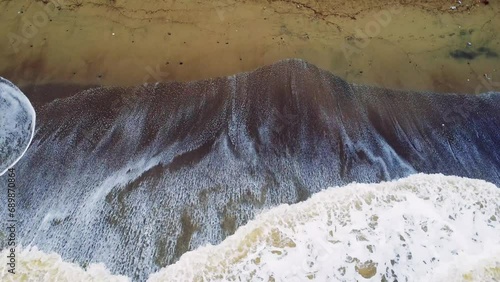 Calming waves roll onto sandy beach at sunset, creating a serene scene. Each wave, a symbol of tranquility, gently caresses the shore. Sunset beachscape, where calming waves meet sandy tranquility