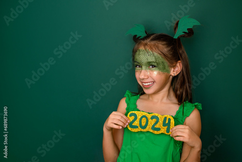 Obraz na plátně A laughing girl with a made-up face in the shape of a dragon shows the numbers of the 2024 new year