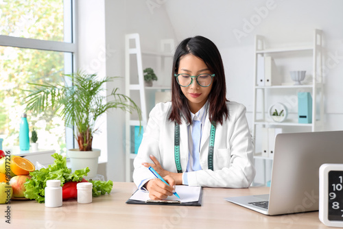 Female Asian nutritionist working at table in office photo