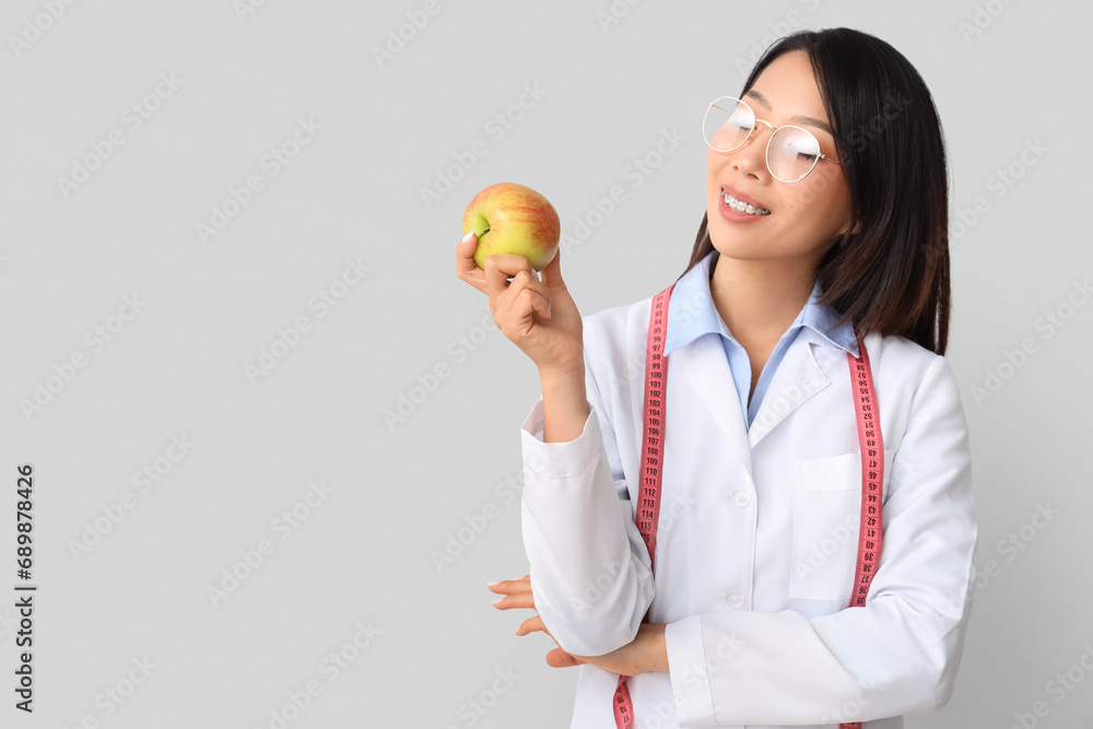 Female Asian nutritionist with apple on light background Female Asian nutritionist with apple on light background