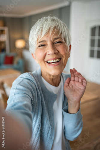 Caucasian mature woman taking selfie or video call using mobile phone
