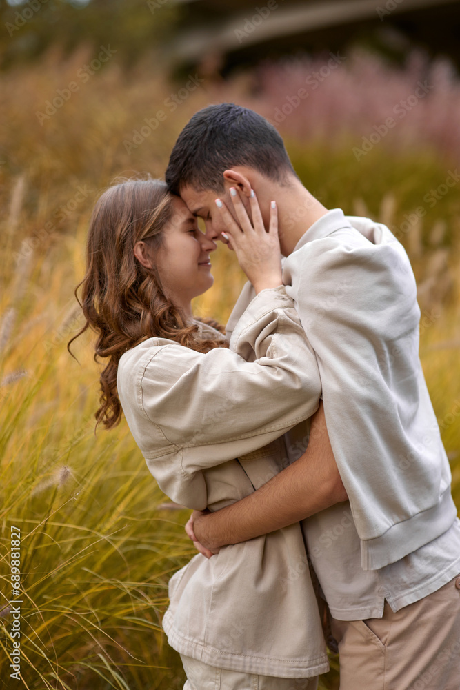 Happy couple on autumn walk outdoors. Two lovers in autumn park. Love and tender touch. Gentle hugs. Young man and woman in classic autumn colors outfit on a romantic date in a cozy park. Young girl Happy couple on autumn walk outdoors. Two lovers in autumn park. Love and tender touch. Gentle hugs. Young man and woman in classic autumn colors outfit on a romantic date in a cozy park. Young girl