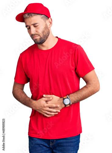 Young handsome blond man wearing t-shirt and cap with hand on stomach because indigestion, painful illness feeling unwell. ache concept.