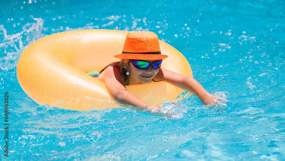 Child in swimming pool on inflatable ring. Kid swim with orange float. Water toy, healthy outdoor sport activity for children. Kids beach fun. Fashion summer kids.