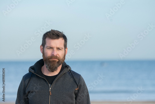 Portrait of man standing on sandy beach. bearded man at beach © VSzili