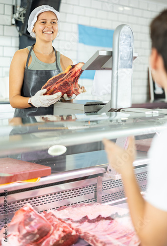 Experienced female butcher skillfully presents various meat options to customer for selection.