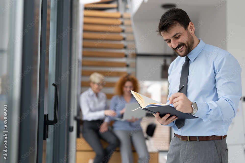 Fototapeta premium Smiling businessman holding notebook at office