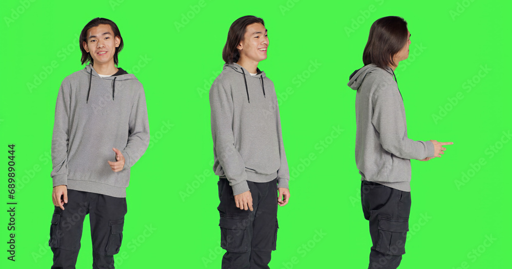 Asian person shows approval sign over greenscreen backdrop, doing yes gesture and smiling. Young man with optimistic facial expressions feeling pleased and expressing agreement. Asian person shows approval sign over greenscreen backdrop, doing yes gesture and smiling. Young man with optimistic facial expressions feeling pleased and expressing agreement.
