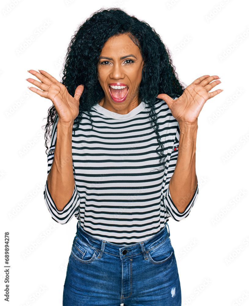 Middle age african american woman wearing casual clothes celebrating crazy and amazed for success with arms raised and open eyes screaming excited. winner concept Middle age african american woman wearing casual clothes celebrating crazy and amazed for success with arms raised and open eyes screaming excited. winner concept