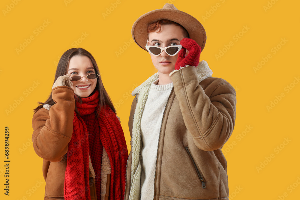 Young couple in winter clothes on yellow background