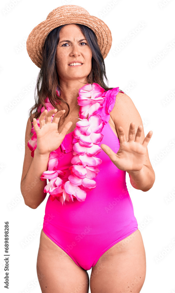 Young beautiful brunette woman wearing swimwear and hawaiian lei disgusted expression, displeased and fearful doing disgust face because aversion reaction. with hands raised Young beautiful brunette woman wearing swimwear and hawaiian lei disgusted expression, displeased and fearful doing disgust face because aversion reaction. with hands raised