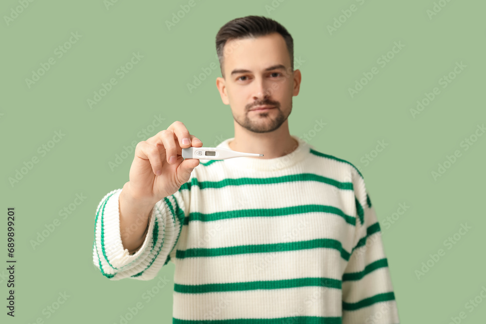 Sick young man with thermometer on green background, closeup Sick young man with thermometer on green background, closeup