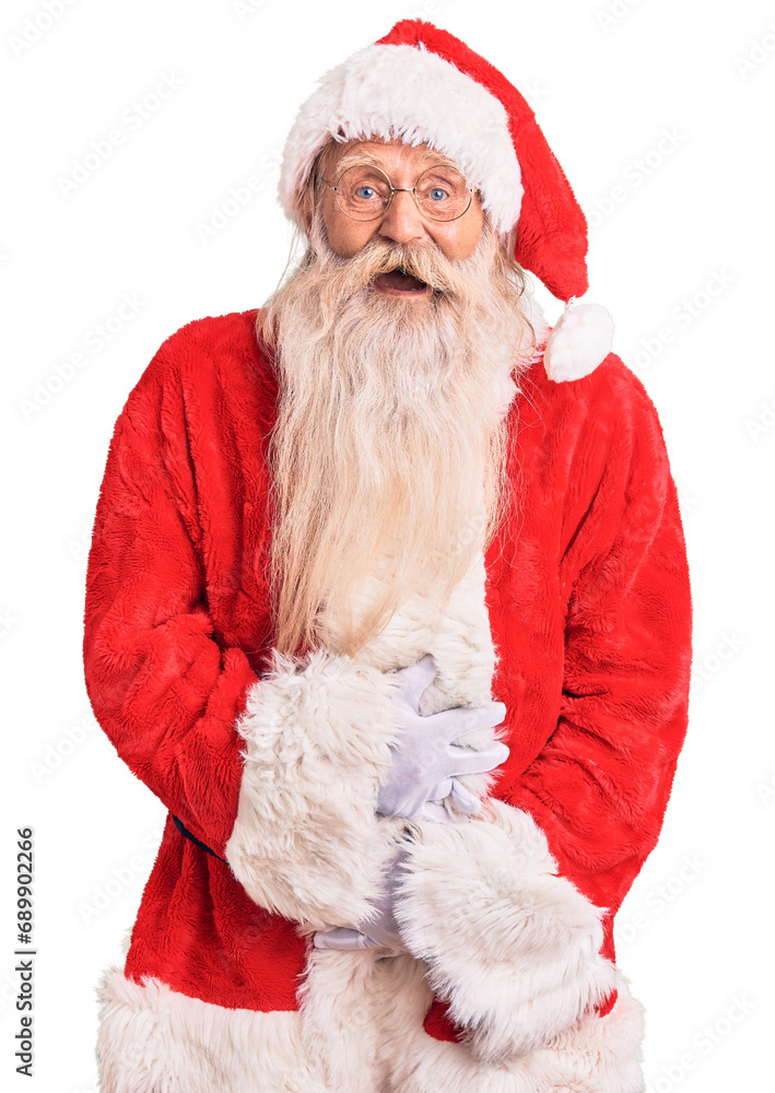 Naklejka premium Old senior man with grey hair and long beard wearing traditional santa claus costume smiling and laughing hard out loud because funny crazy joke with hands on body.