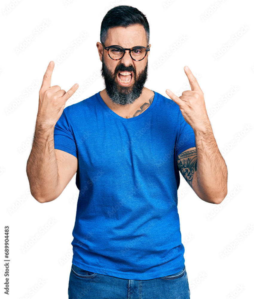 Hispanic man with beard wearing casual t shirt and glasses shouting with crazy expression doing rock symbol with hands up. music star. heavy concept. Hispanic man with beard wearing casual t shirt and glasses shouting with crazy expression doing rock symbol with hands up. music star. heavy concept.