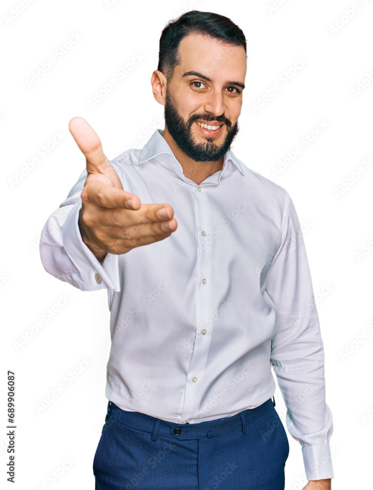 Young man with beard wearing business shirt smiling friendly offering handshake as greeting and welcoming. successful business. Young man with beard wearing business shirt smiling friendly offering handshake as greeting and welcoming. successful business.