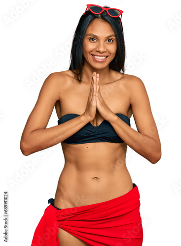 Young african american woman wearing bikini praying with hands together asking for forgiveness smiling confident.