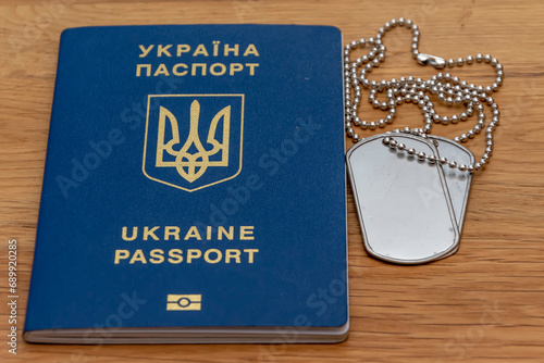 Ukrainian passport and army medallion on textured wooden background. Concept: military conscription and mobilization of the militarily liable.