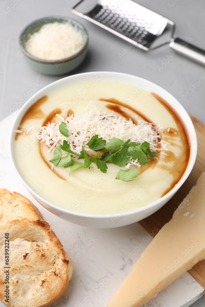 Delicious cream soup with parmesan cheese, soy sauce in bowl and croutons on light grey table Delicious cream soup with parmesan cheese, soy sauce in bowl and croutons on light grey table