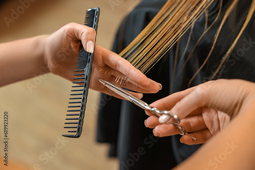 Professional hairdresser cutting girl's hair in beauty salon, closeup