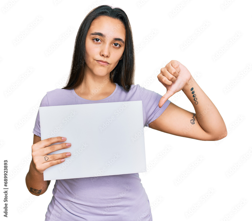 Young hispanic woman holding blank empty banner with angry face, negative sign showing dislike with thumbs down, rejection concept Young hispanic woman holding blank empty banner with angry face, negative sign showing dislike with thumbs down, rejection concept