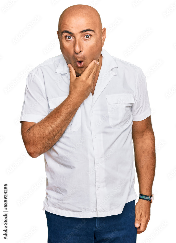 Mature middle east man with mustache wearing casual white shirt looking fascinated with disbelief, surprise and amazed expression with hands on chin Mature middle east man with mustache wearing casual white shirt looking fascinated with disbelief, surprise and amazed expression with hands on chin