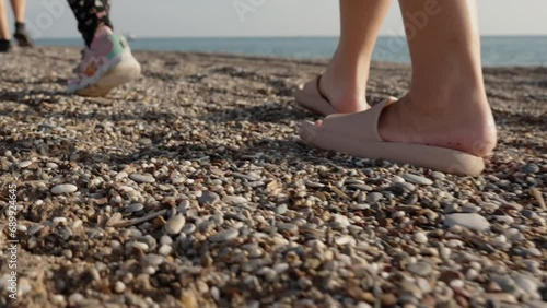 Family Stroll on the Seaside Beach, Child and a Man with a Woman Stepping on the Rocks. View From Below, Slow Motion. photo