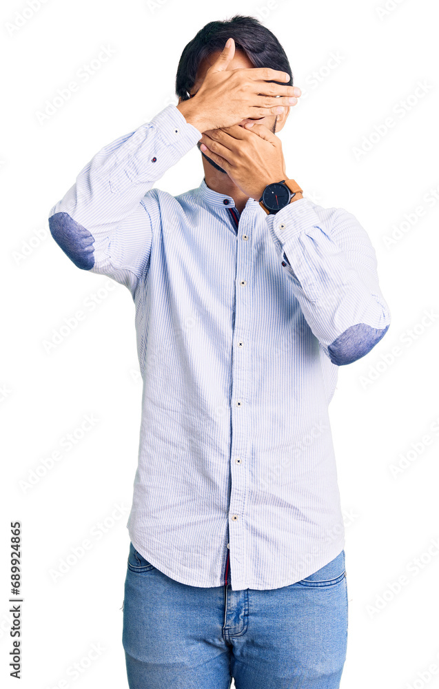 Handsome hispanic man wearing business shirt and glasses covering eyes and mouth with hands, surprised and shocked. hiding emotion Handsome hispanic man wearing business shirt and glasses covering eyes and mouth with hands, surprised and shocked. hiding emotion