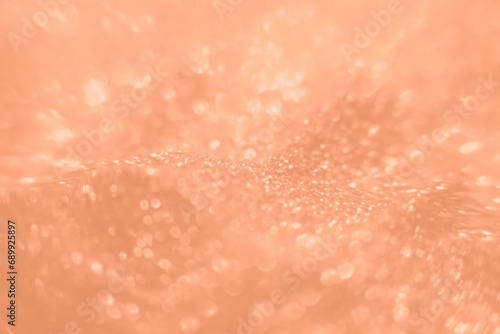 Peach Fuzz color glitter background. Blurred monochrome background with bokeh. Blurred glitters shimmering dust macro close up.