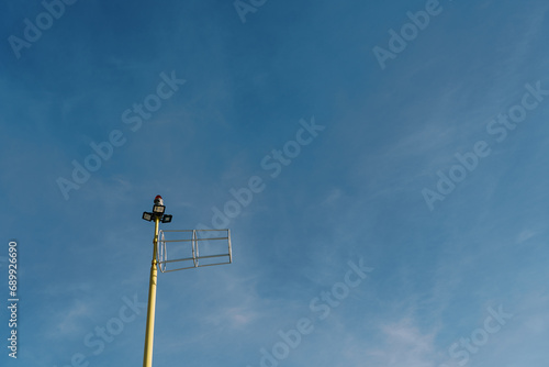Antenna on a pole with searchlights and a signal lantern on the top against the sky