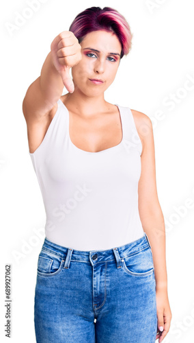 Young beautiful woman with pink hair wearing casual clothes looking unhappy and angry showing rejection and negative with thumbs down gesture. bad expression.