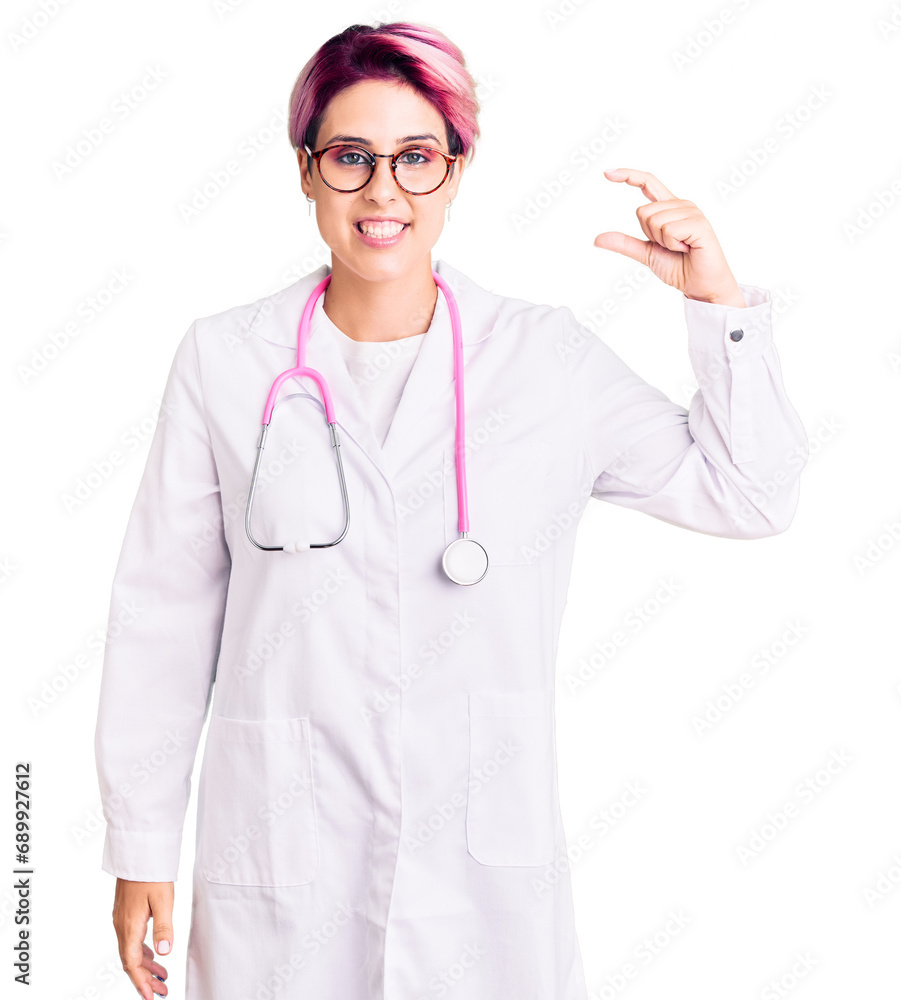 Young beautiful woman with pink hair wearing doctor uniform smiling and confident gesturing with hand doing small size sign with fingers looking and the camera. measure concept. Young beautiful woman with pink hair wearing doctor uniform smiling and confident gesturing with hand doing small size sign with fingers looking and the camera. measure concept.