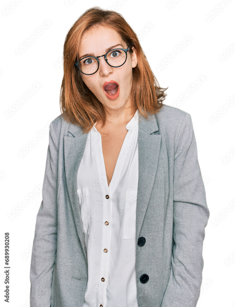 Young caucasian woman wearing business style and glasses in shock face, looking skeptical and sarcastic, surprised with open mouth Young caucasian woman wearing business style and glasses in shock face, looking skeptical and sarcastic, surprised with open mouth