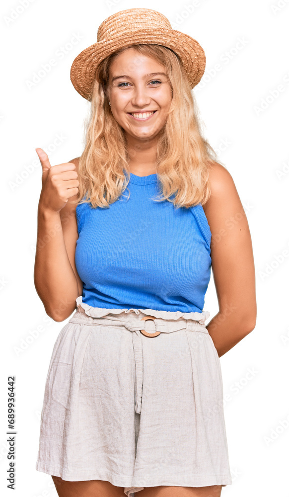 Young blonde girl wearing summer hat smiling happy and positive, thumb up doing excellent and approval sign Young blonde girl wearing summer hat smiling happy and positive, thumb up doing excellent and approval sign