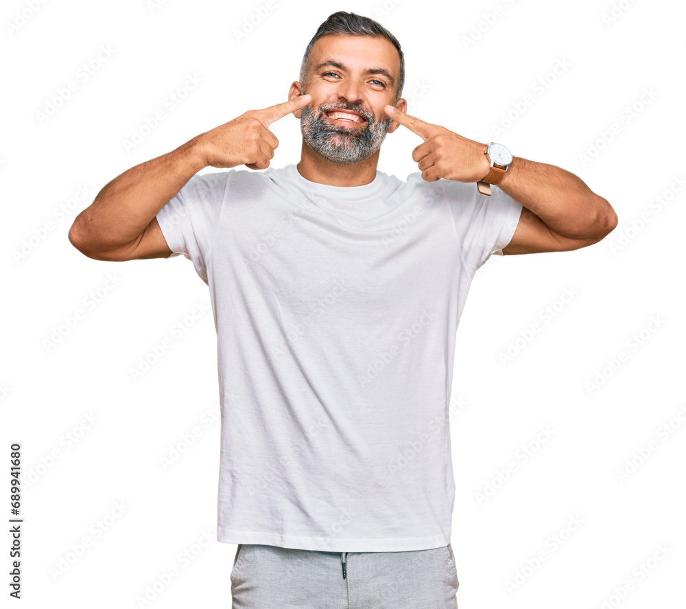 Middle age handsome man wearing casual white tshirt smiling cheerful showing and pointing with fingers teeth and mouth. dental health concept. Middle age handsome man wearing casual white tshirt smiling cheerful showing and pointing with fingers teeth and mouth. dental health concept.
