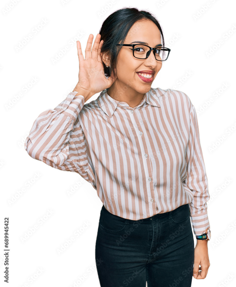 Young hispanic girl wearing casual clothes and glasses smiling with hand over ear listening an hearing to rumor or gossip. deafness concept. Young hispanic girl wearing casual clothes and glasses smiling with hand over ear listening an hearing to rumor or gossip. deafness concept.