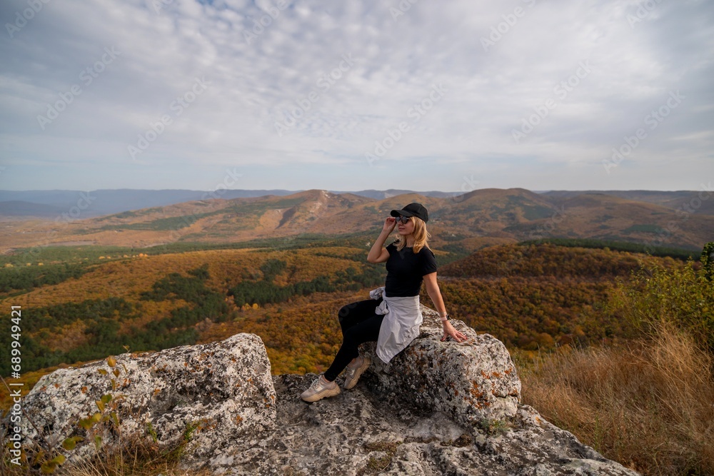 woman on mountain peak looking in beautiful mountain valley in autumn. Landscape with sporty young woman, blu sky in fall. Hiking. Nature