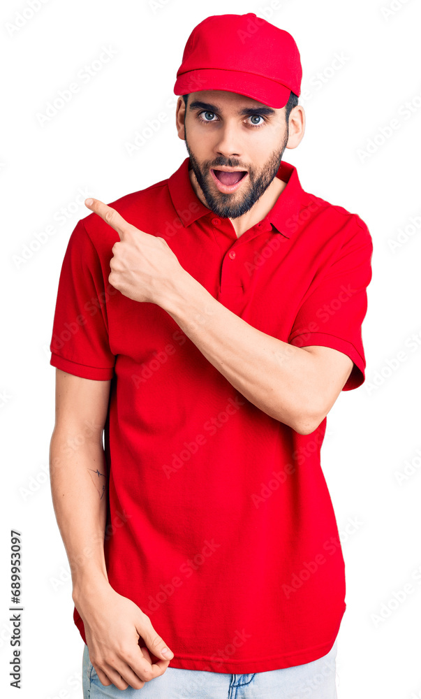 Young handsome man with beard wearing delivery uniform surprised pointing with finger to the side, open mouth amazed expression. Young handsome man with beard wearing delivery uniform surprised pointing with finger to the side, open mouth amazed expression.