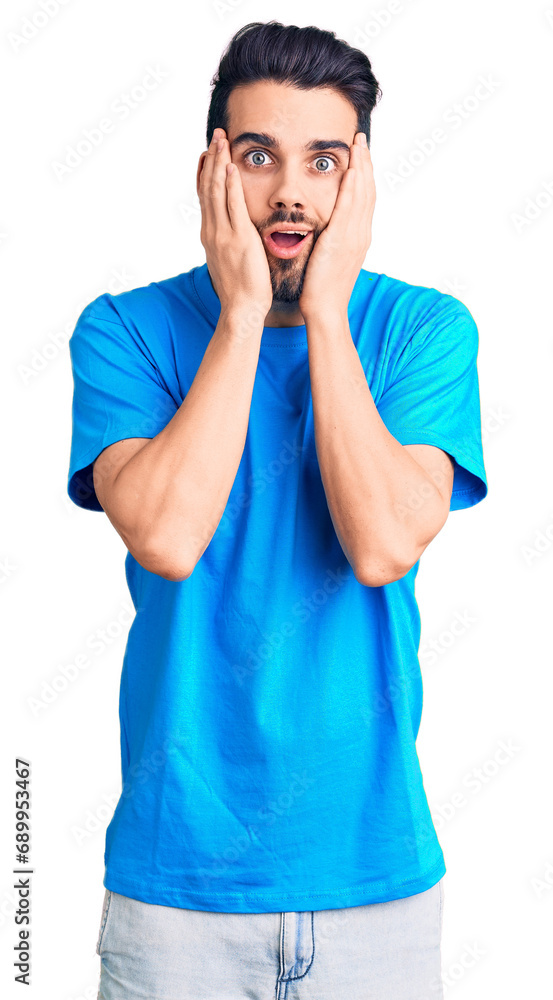 Young handsome man with beard wearing casual t-shirt afraid and shocked, surprise and amazed expression with hands on face Young handsome man with beard wearing casual t-shirt afraid and shocked, surprise and amazed expression with hands on face