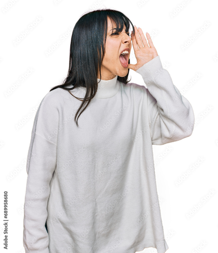 Young brunette woman with bangs wearing casual turtleneck sweater shouting and screaming loud to side with hand on mouth. communication concept. Young brunette woman with bangs wearing casual turtleneck sweater shouting and screaming loud to side with hand on mouth. communication concept.